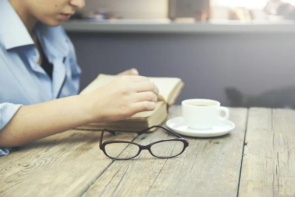 Mulher sentada à mesa de madeira e livro de leitura — Fotografia de Stock