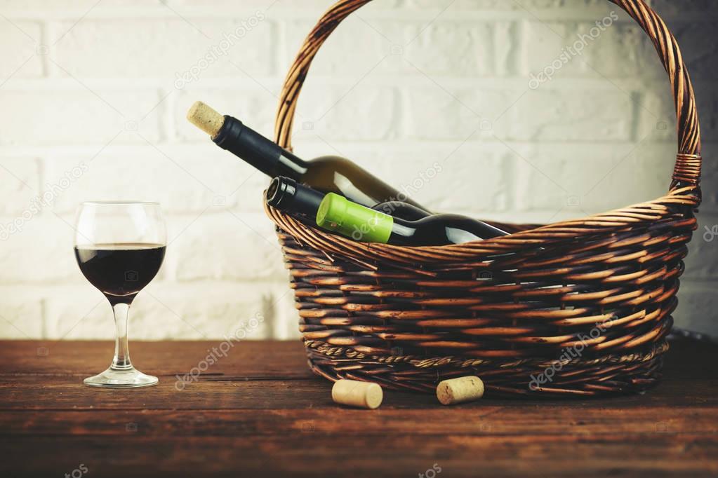 Wine bottles in basket on wooden table