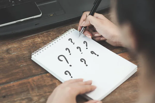 woman writing question marks