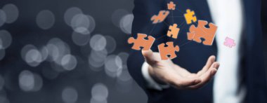 Ofisinde elini uçan puzzle parçaları tutan işadamı