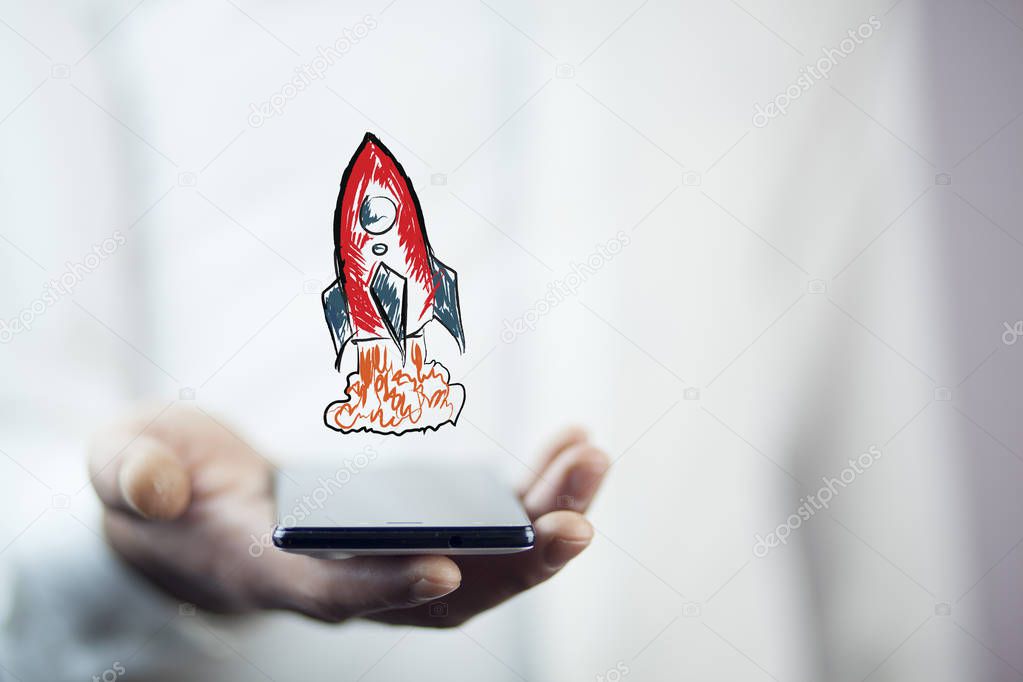 Businessman holding  phone with red rocket icon above 