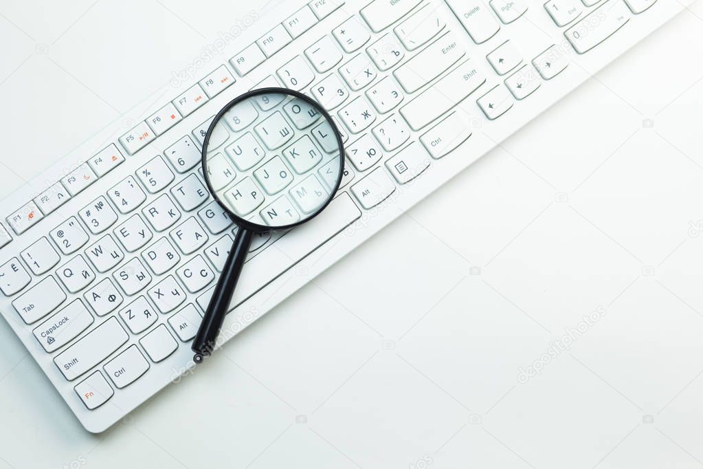 magnifying glass on computer keyboard, close up