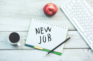 Not defteri ve klavye, kahve ve elma tablo üzerinde yeni iş kelimeleri