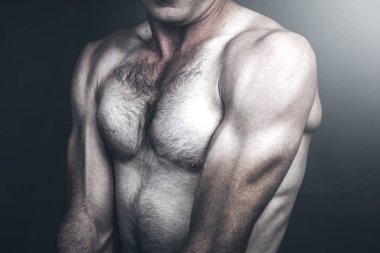 Oturan kaslı genç adam.