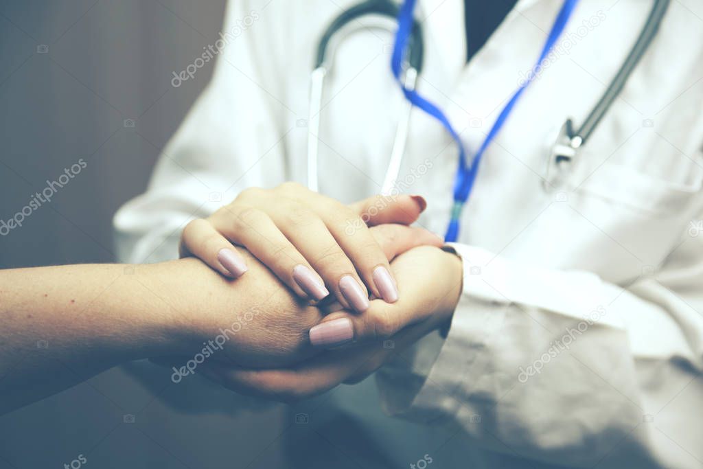 woman doctor's hands holding female patient's hand for encourage