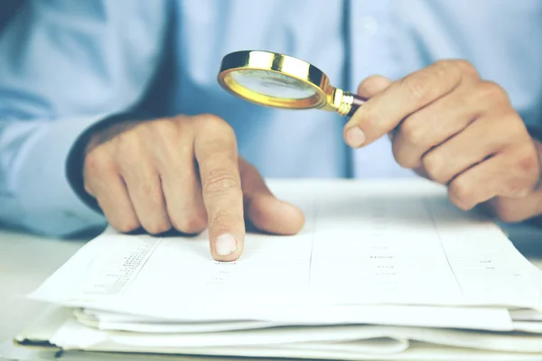 Affärsman tittar på dokumentet genom förstoringsglas — Stockfoto