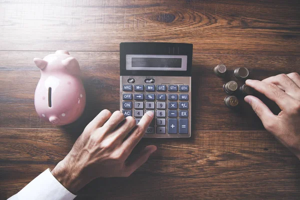 Affärsman hand kalkylator och spargris bank — Stockfoto