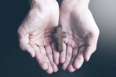 businessman hand wooden cross in dark background