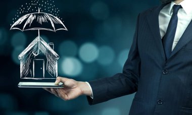Businessman hand tablet with umbrella over house