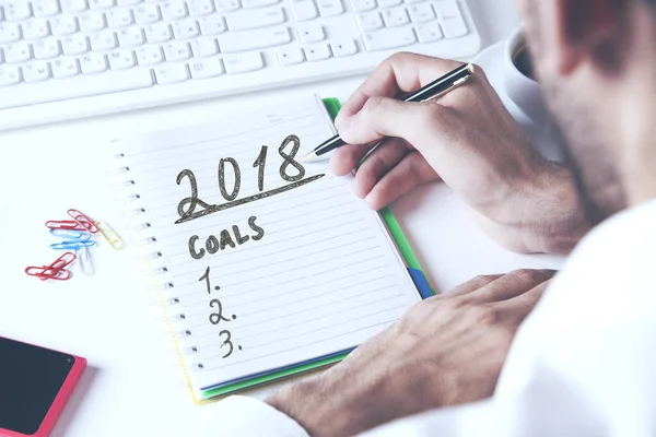 Businessman hand on keyboard  and writing  2018 goals on table — Stock Photo, Image