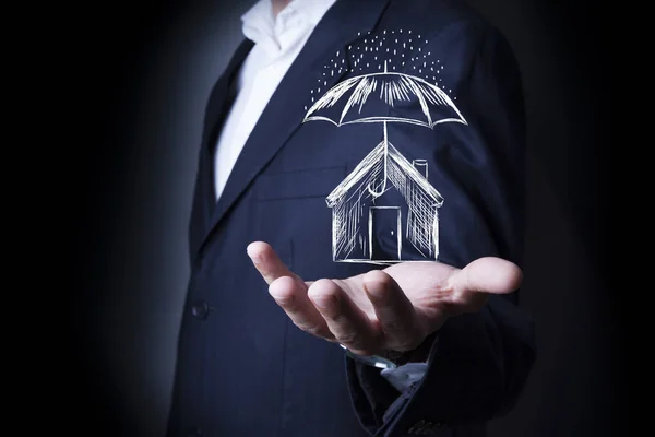Businessman drawing umbrella over house