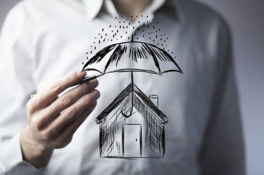 Businessman hand pen with umbrella over house