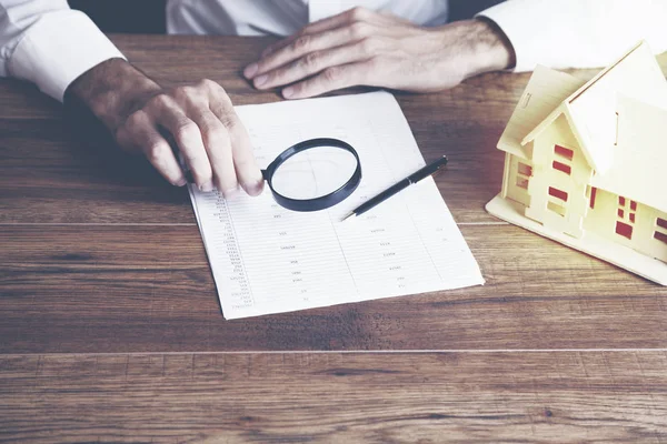 Lente d'ingrandimento mano uomo d'affari e documento con il prossimo modello di casa — Foto Stock