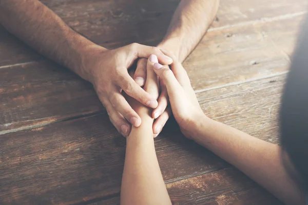 Cerca de un hombre y una mujer tomados de la mano en una mesa de madera —  Fotos de Stock