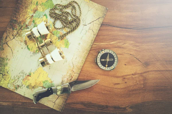 Vintage binoculars, compass, pocket knife on map