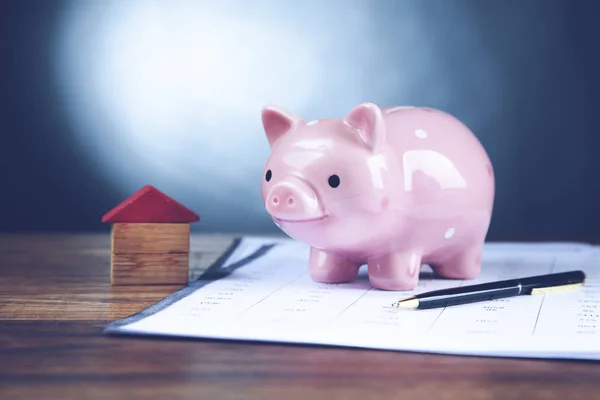 Piggy bank and house model on document — Stock Photo, Image