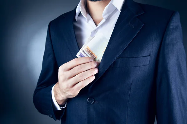 En affärsman i kostym att lägga pengar i fickan — Stockfoto