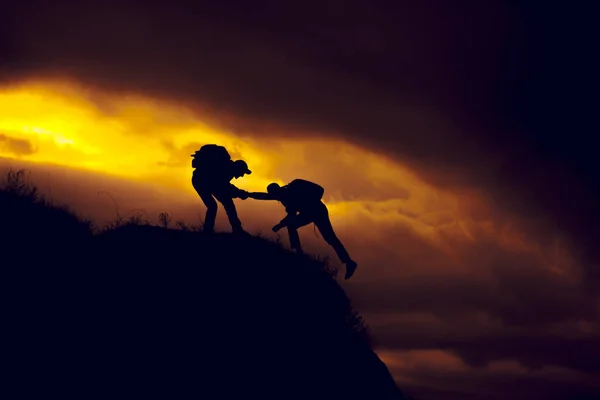 Silhouet van helpende hand tussen twee klimmer — Stockfoto