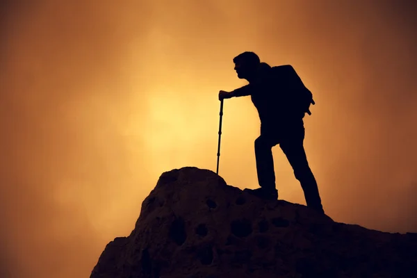 Een man die op de top van de berg boven de wolken. — Stockfoto