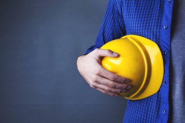 Kolunun altında kask tutan bir adam. 