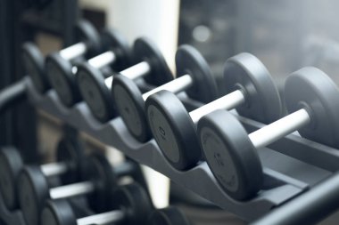 Karanlık ağırlık odasında bir sürü siyah dambıl var.