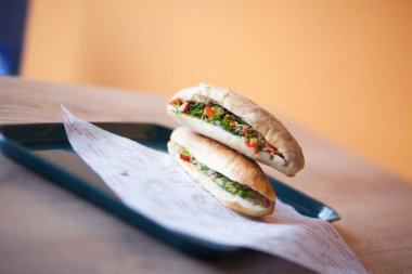 Hardallı, turşulu, domatesli, çeşnili ve soğanlı sosisli sandviç.