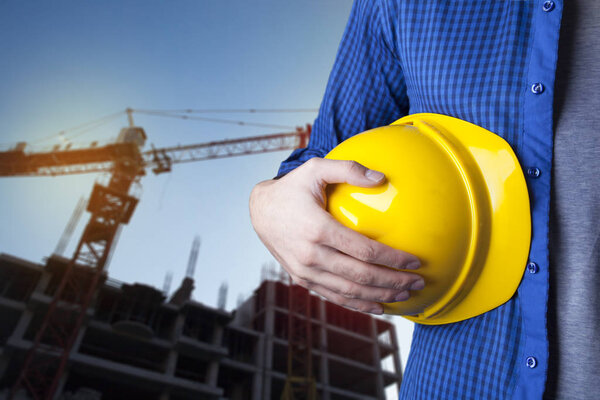 Engineer holding a yellow helmet for the safety of construction 