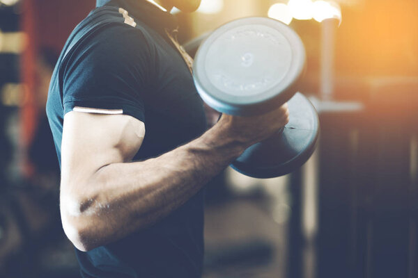 athletic man in training pumping up muscles with dumbbells.