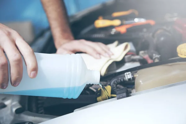 Auto mechanic hand holding motor oil on car background