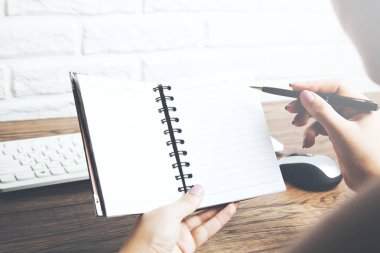 Not defteri, kalem ve bilgisayar klavyesi olan kadın elleri