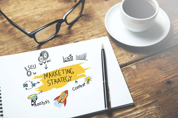 текст стратегии маркетинга на блокноте с кофе на столе