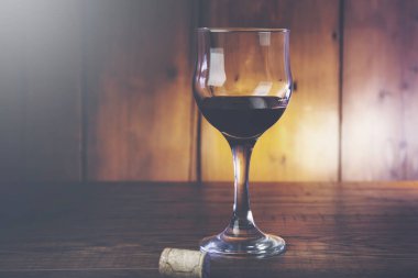 Ahşap masa arkasında bir kadeh şarap.