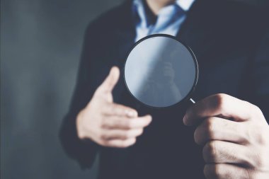 Koyu arkaplanda iş adamı eli büyüteci