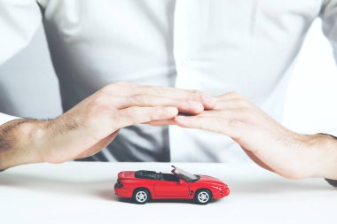 Araba sigortası konsepti. Masadaki adam ve arabanın modeli.
