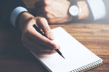 Ahşap masa arkasına not defterine bir adam yazılmış.