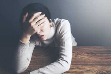 Eldeki üzgün bir kadın masada oturuyor.