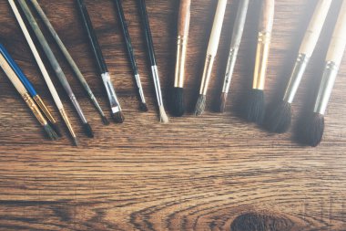 Ahşap masa arkasında çeşitli boya fırçaları koleksiyonu