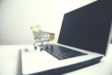 Beyaz arka planda dizüstü bilgisayarda alışveriş sepeti