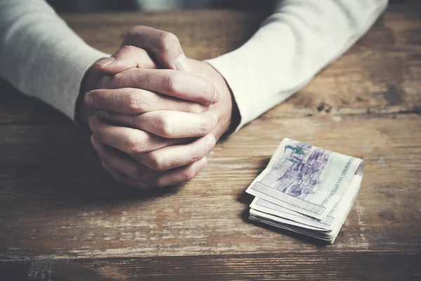 Man pray hand and money on table