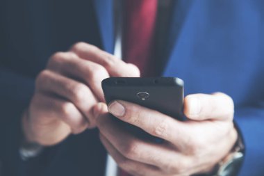 Genç bir adam kanepede oturuyor ve akıllı bir telefon kullanıyor.