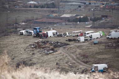 Vadide bitkilerle çevrili renkli makinelerle dolu bir hurdalık.