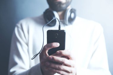 Adam akıllı telefondan müzik dinliyor.