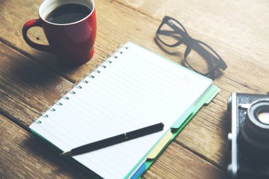 Masada kahve ve kamera olan not defteri.