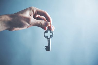 Adam eski anahtarı karanlık arka planda tutuyor.