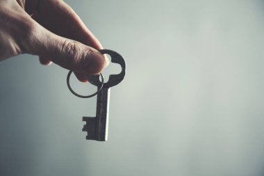 Adam eski anahtarı karanlık arka planda tutuyor.