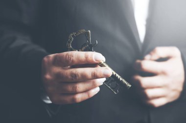 Adam eski anahtarı karanlık arka planda tutuyor.