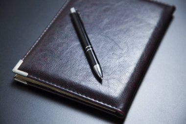 Koyu arkaplanda kalem üzerine not defteri