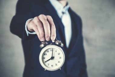 İş adamı saati elinde tutuyor.
