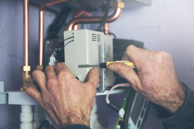 Teknisyen sıcak su ve ısıtma için gaz kazanına bakıyor.