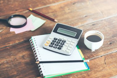 Not defterinde hesap makinesi ve masada kahve.